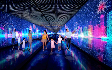 Families walking through the Time Capsule at Singapore Flyer with digital cityscape and fireworks.