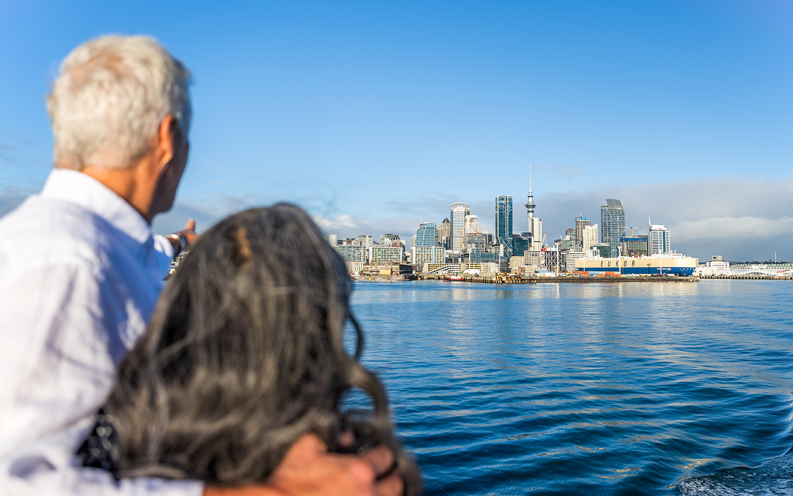 Couple admiring Auckland cityscape from the water, New Zealand.