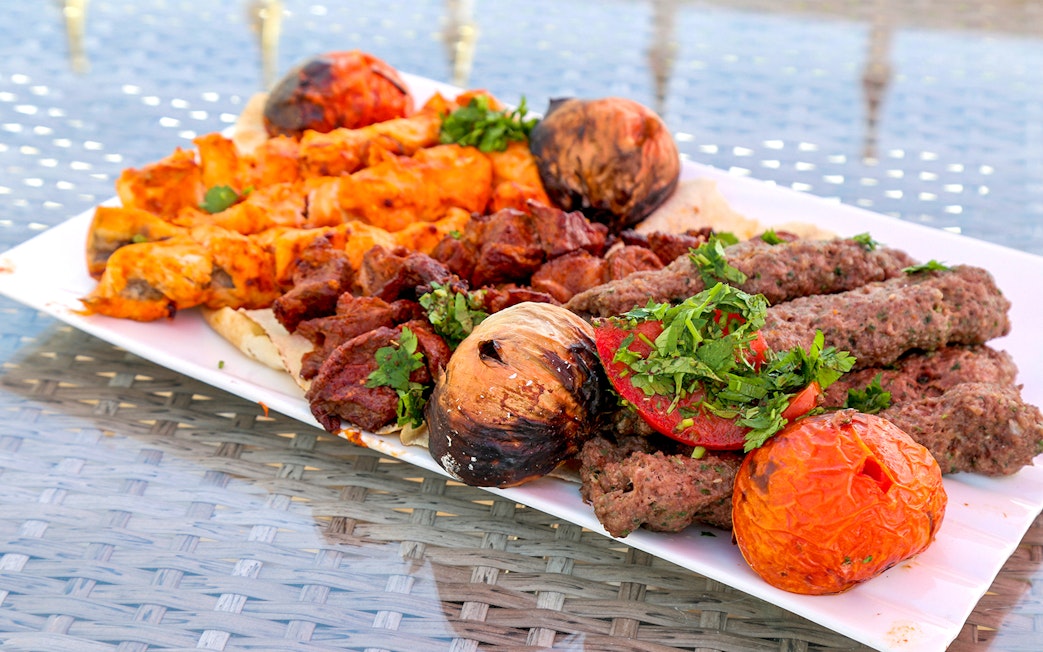 Grilled kebabs and vegetables on a plate during Abu Dhabi city tour from Dubai.