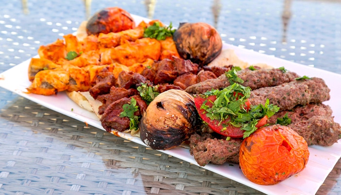 Grilled kebabs and vegetables on a plate during Abu Dhabi city tour from Dubai.