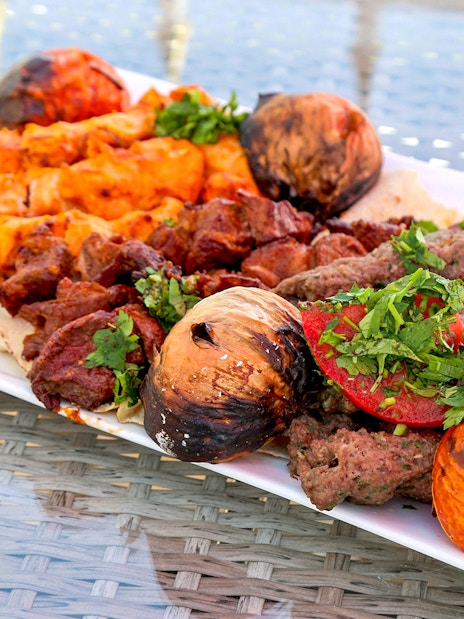Grilled kebabs and vegetables on a plate during Abu Dhabi city tour from Dubai.