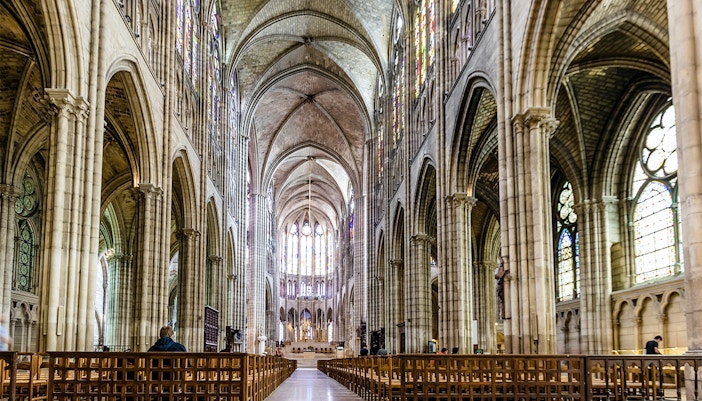 Interior of Basilica of Saint-Denis, showcasing Gothic architecture and stained glass windows.