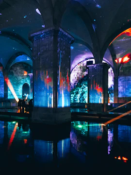 Immersive light show in an underground vaulted space with colorful projections.