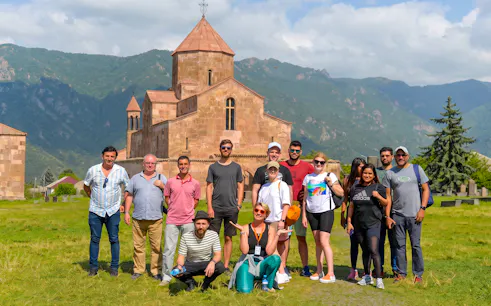 Group of tourists on a guided tour in front of Odzun Church, Armenia.