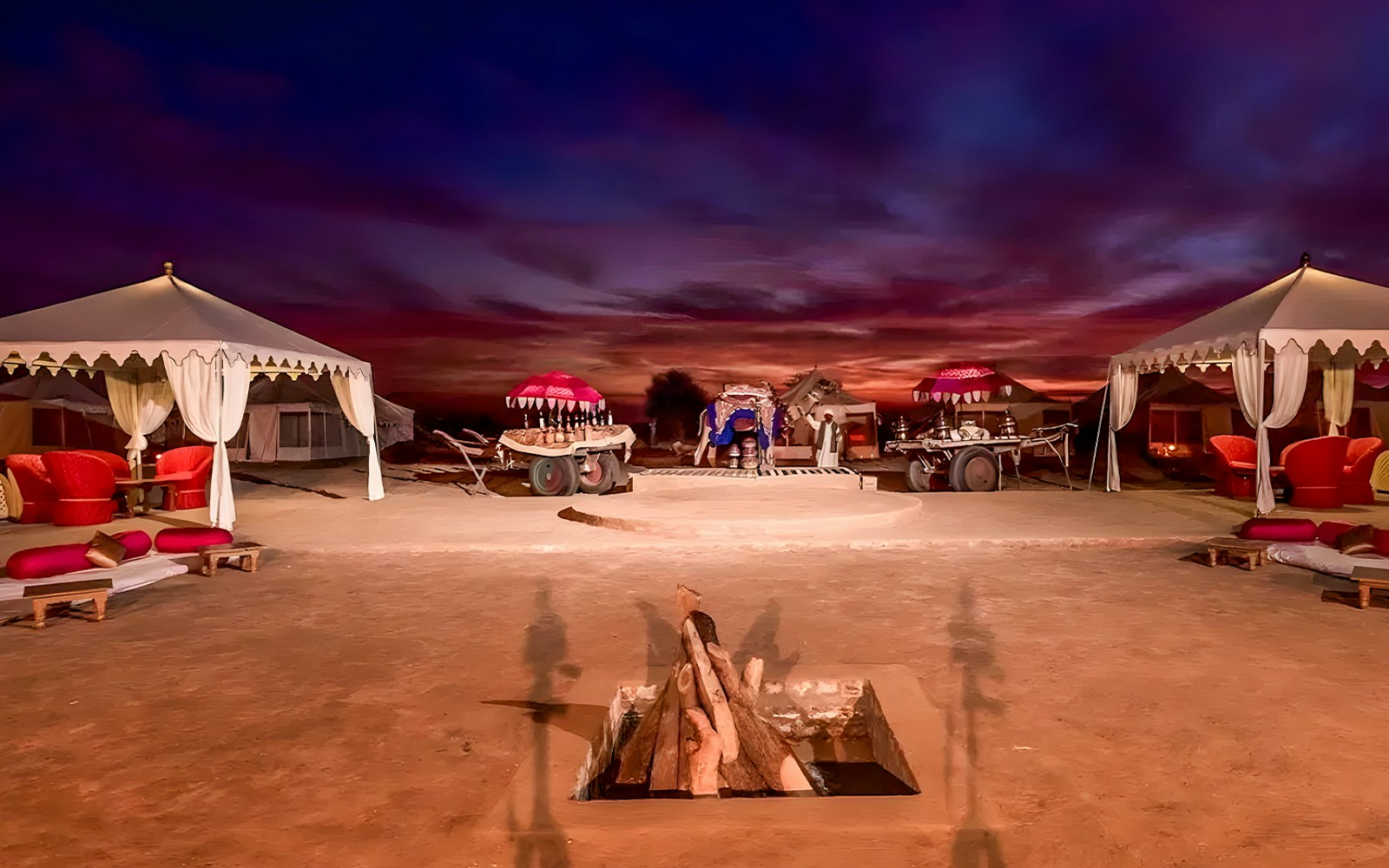 Desert camp setup at sunset with tents and seating for an evening safari experience.