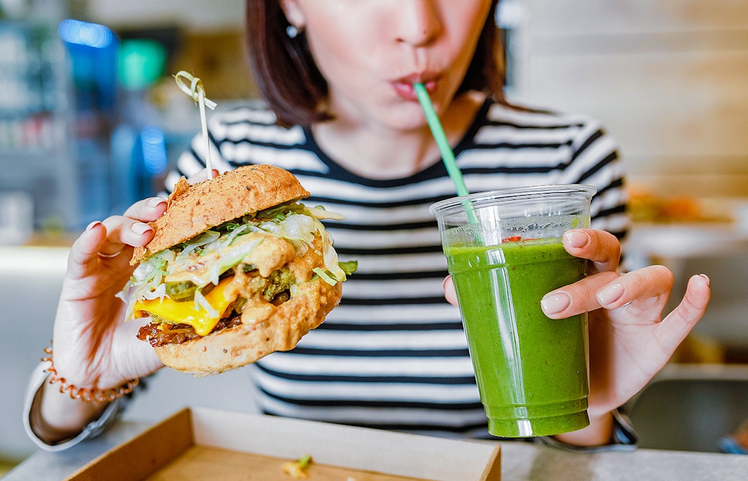 Vegan burger and smoothie served at a cafe table.