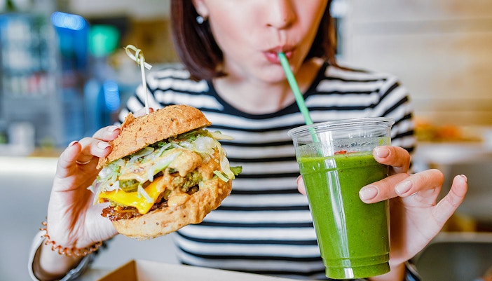 Burger and green smoothie in a cafe setting.