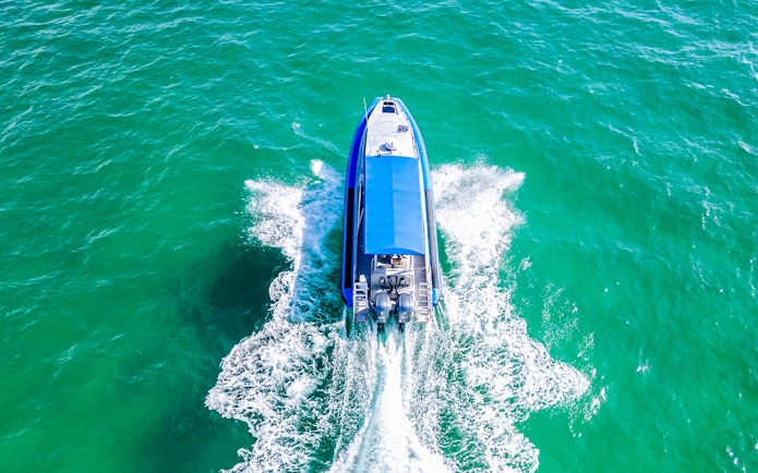 Boat cruising on Lake Macquarie, Australia, creating a wake in turquoise water.