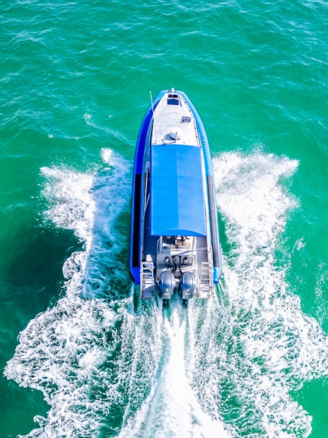 Boat cruising on Lake Macquarie, Australia, creating a wake in turquoise water.