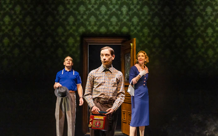 Three people in vintage attire stand in a dimly lit room, one holding a retro radio.