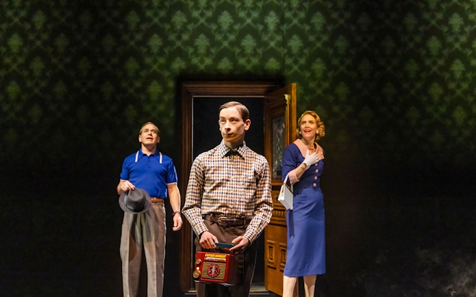 Three people in vintage attire stand in a dimly lit room, one holding a retro radio.