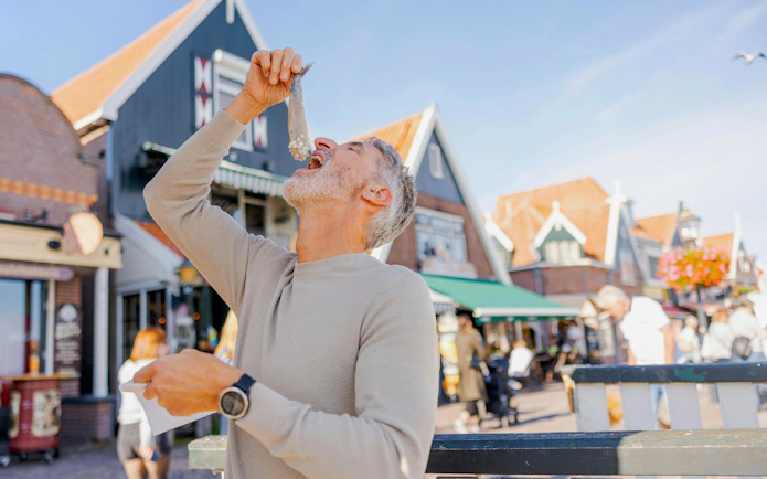 Man eating Dutch soused herring in Volendam street.
