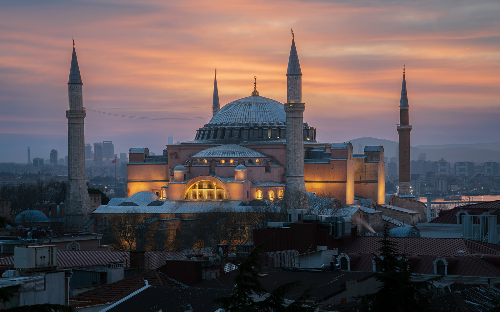 Hagia Sophia Grand Mosque at sunset, Istanbul skyline in the background.