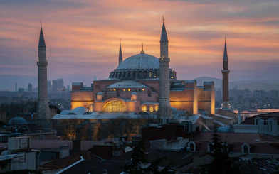 Hagia Sophia Grand Mosque at sunset, Istanbul skyline in the background.