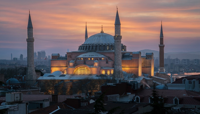 Hagia Sophia Grand Mosque at sunset, Istanbul skyline in the background.