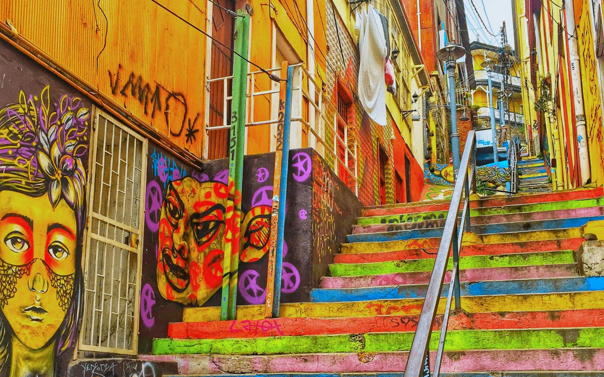 Colorful staircase with vibrant street art murals in Valparaíso, Chile.