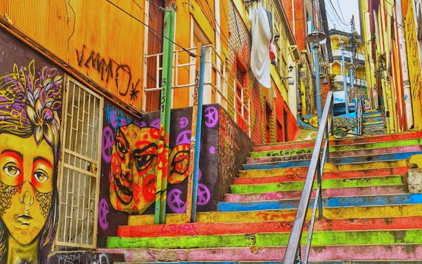 Colorful staircase with vibrant street art murals in Valparaíso, Chile.