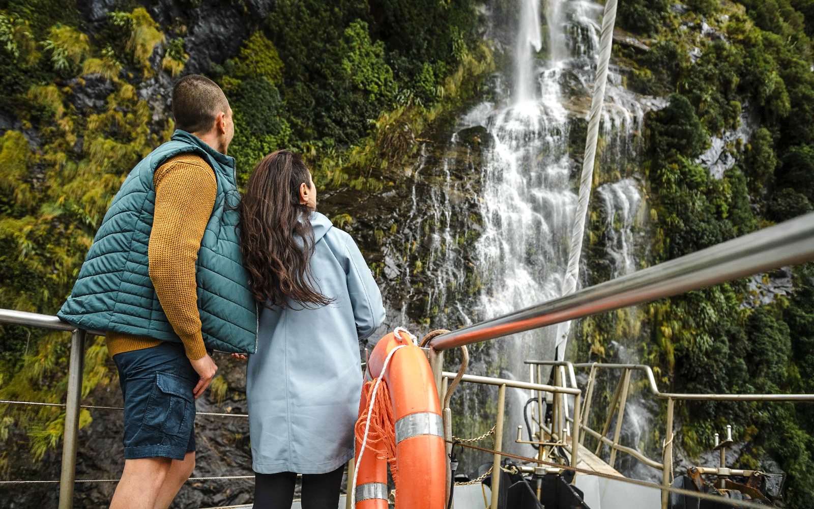 Couple on Doubtful Sound cruise viewing waterfall.