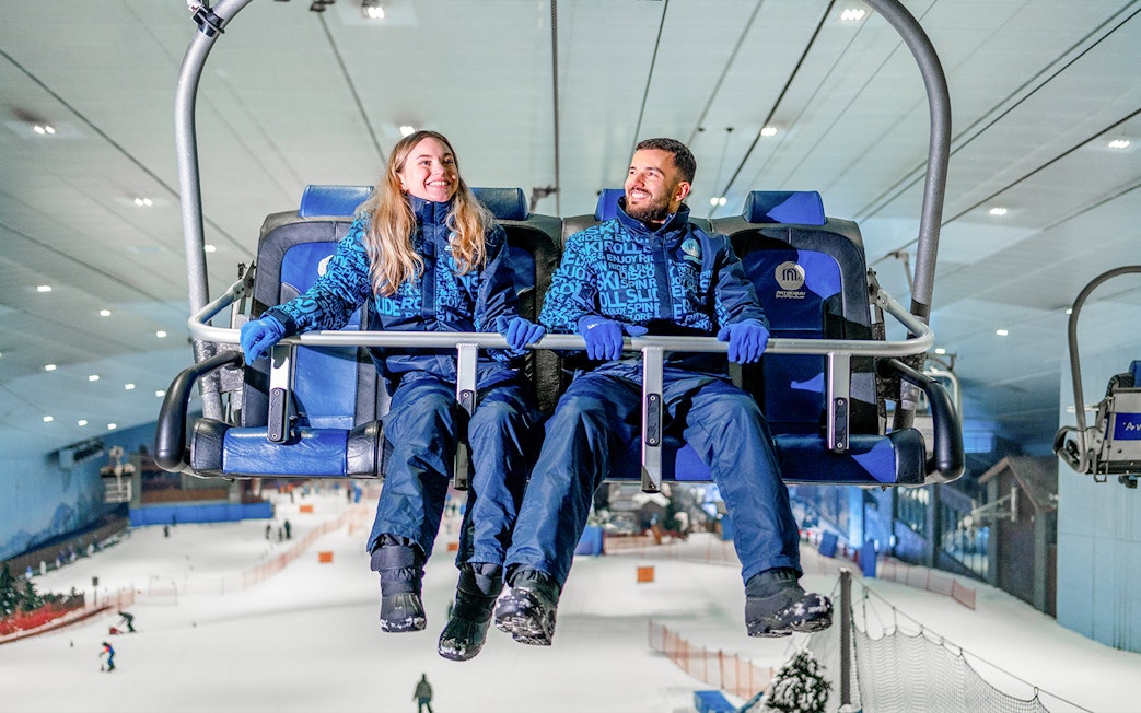 Couple on a chairlift at Ski Dubai indoor ski resort.