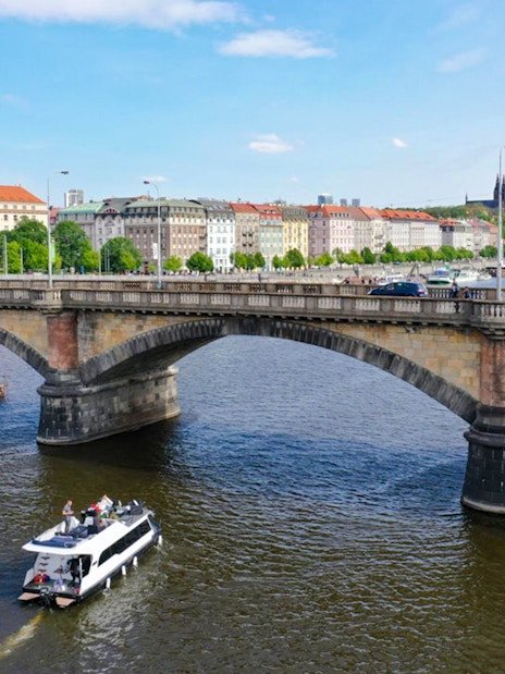 Prague yacht boat cruising near Charles Bridge on the Vltava River.