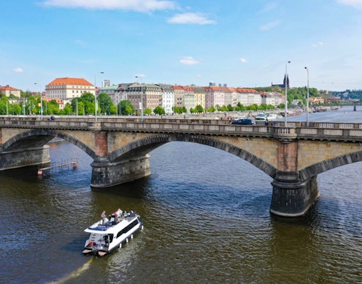 Prague yacht boat cruising near Charles Bridge on Vltava River.