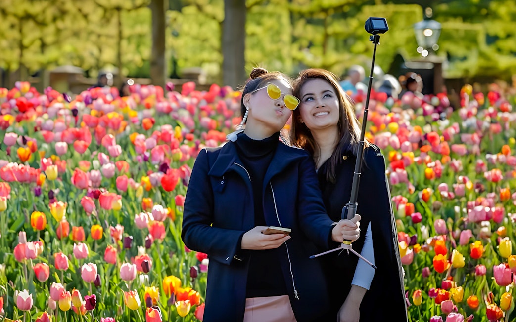 Visitors taking a selfie among colorful tulips at Keukenhof Gardens.