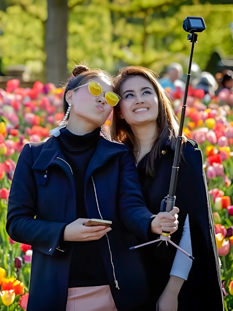 Visitors taking a selfie among colorful tulips at Keukenhof Gardens.
