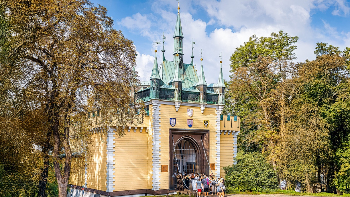 Exterior view of the Mirror Maze entrance with visitors in front, surrounded by trees.
