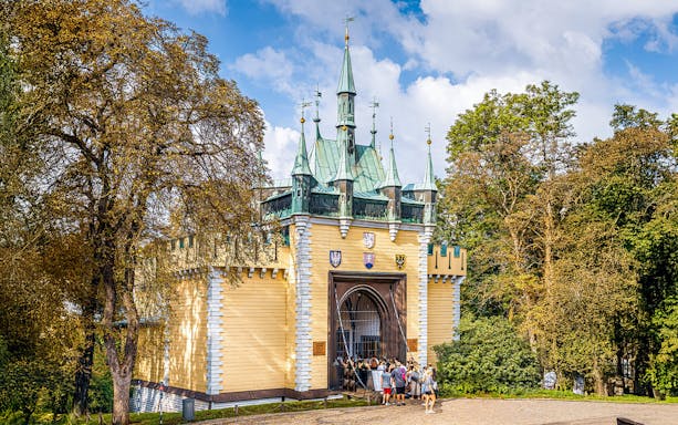 Exterior view of the Mirror Maze entrance with visitors in front, surrounded by trees.