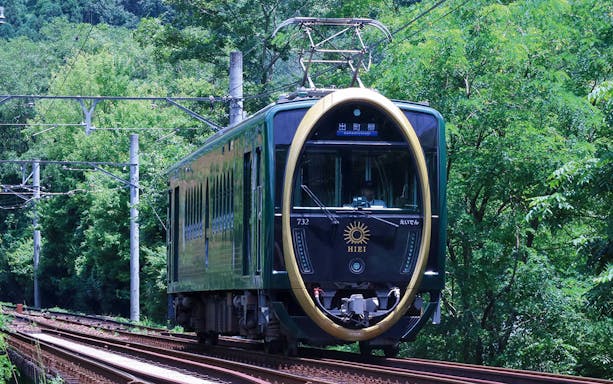 Train on tracks surrounded by lush greenery in Kyoto's Kurama and Kibune area.