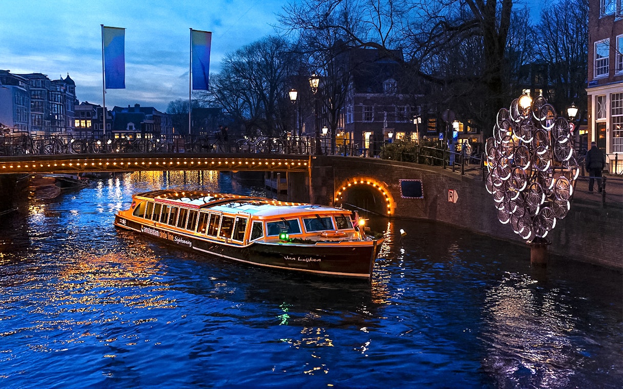 Traditional canal boat cruising during Amsterdam Light Festival.