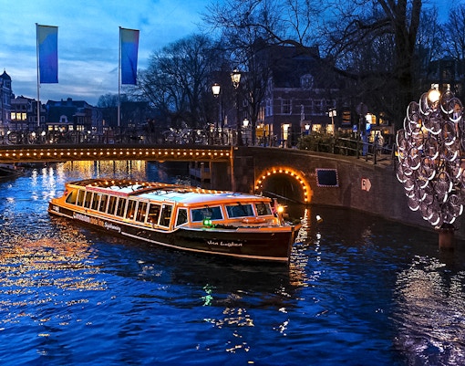 Traditional canal boat cruising during Amsterdam Light Festival.