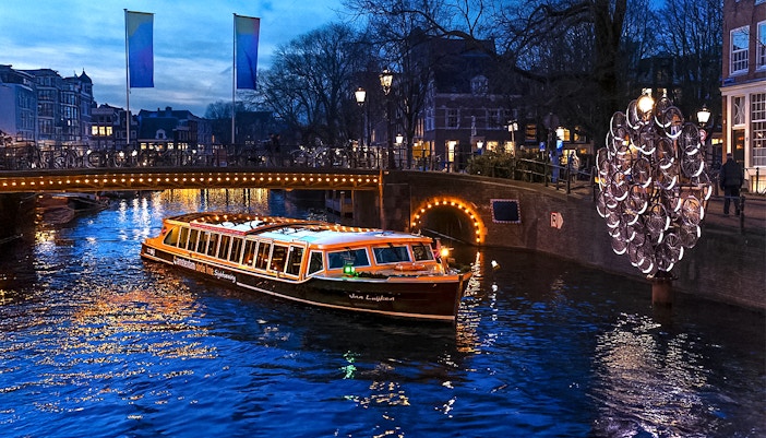 Traditional canal boat cruising during Amsterdam Light Festival.