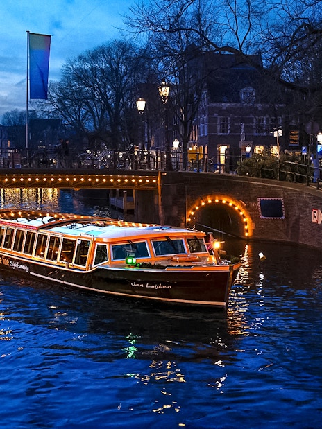 Traditional canal boat cruising during Amsterdam Light Festival.