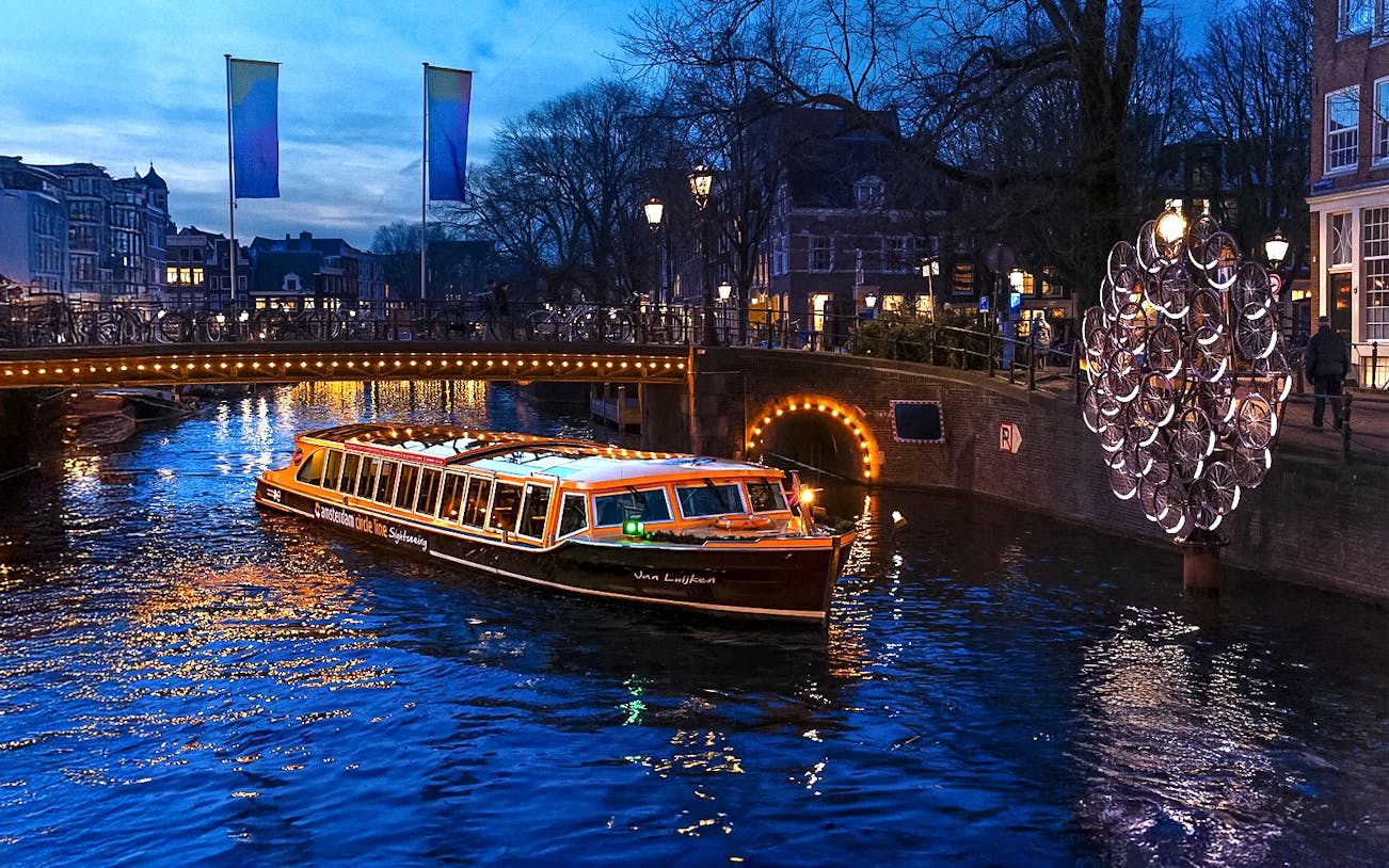 Traditional canal boat cruising during Amsterdam Light Festival.
