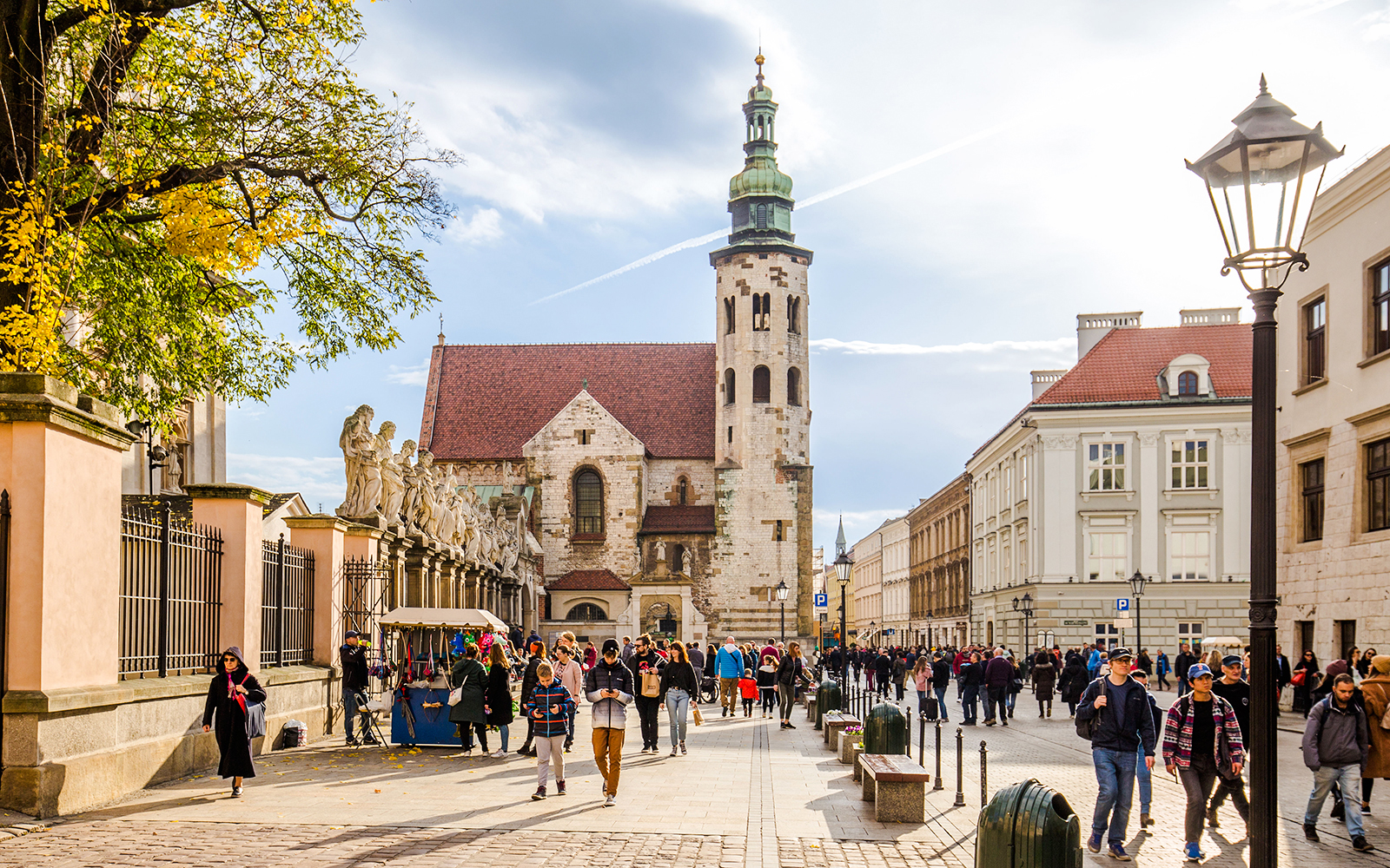 Crowded street in Jewish Quarter Kazimierz, Krakow with historic church and market stalls.