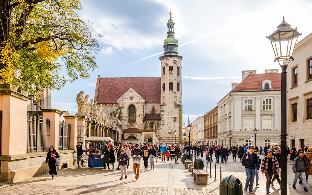 Crowded street in Jewish Quarter Kazimierz, Krakow with historic church and market stalls.
