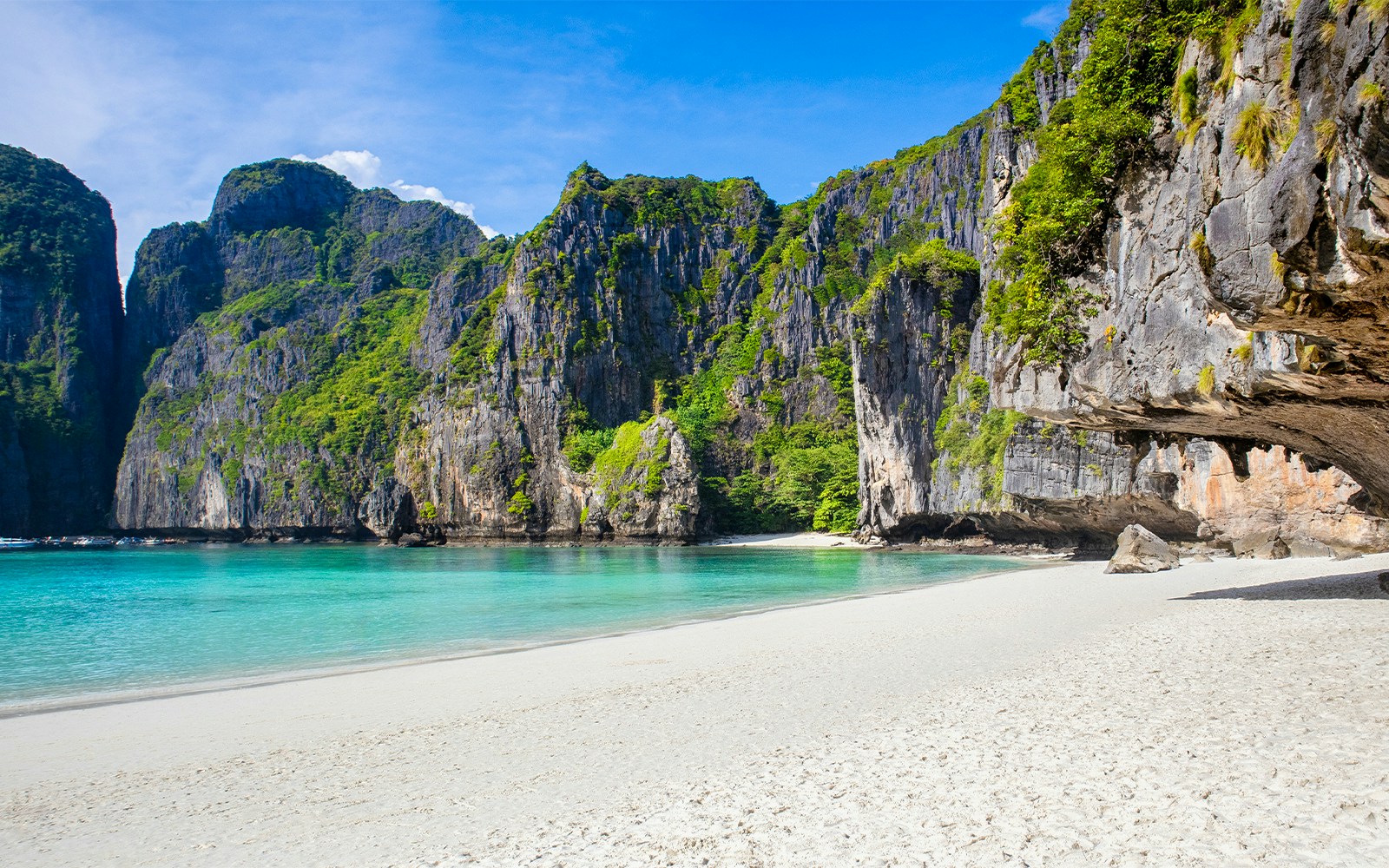 Maya Beach shoreline with turquoise waters and limestone cliffs, Phi Phi Islands, Thailand.