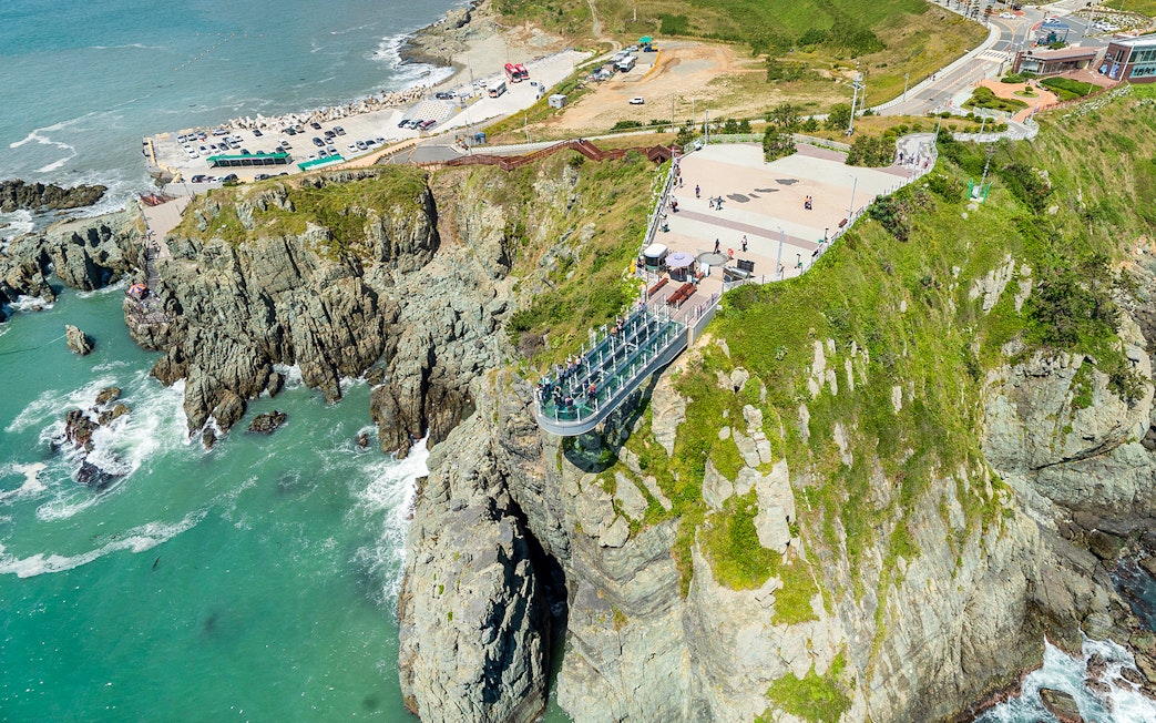 Cliffside view of Blueline Park Sky Capsule in Busan with ocean backdrop.