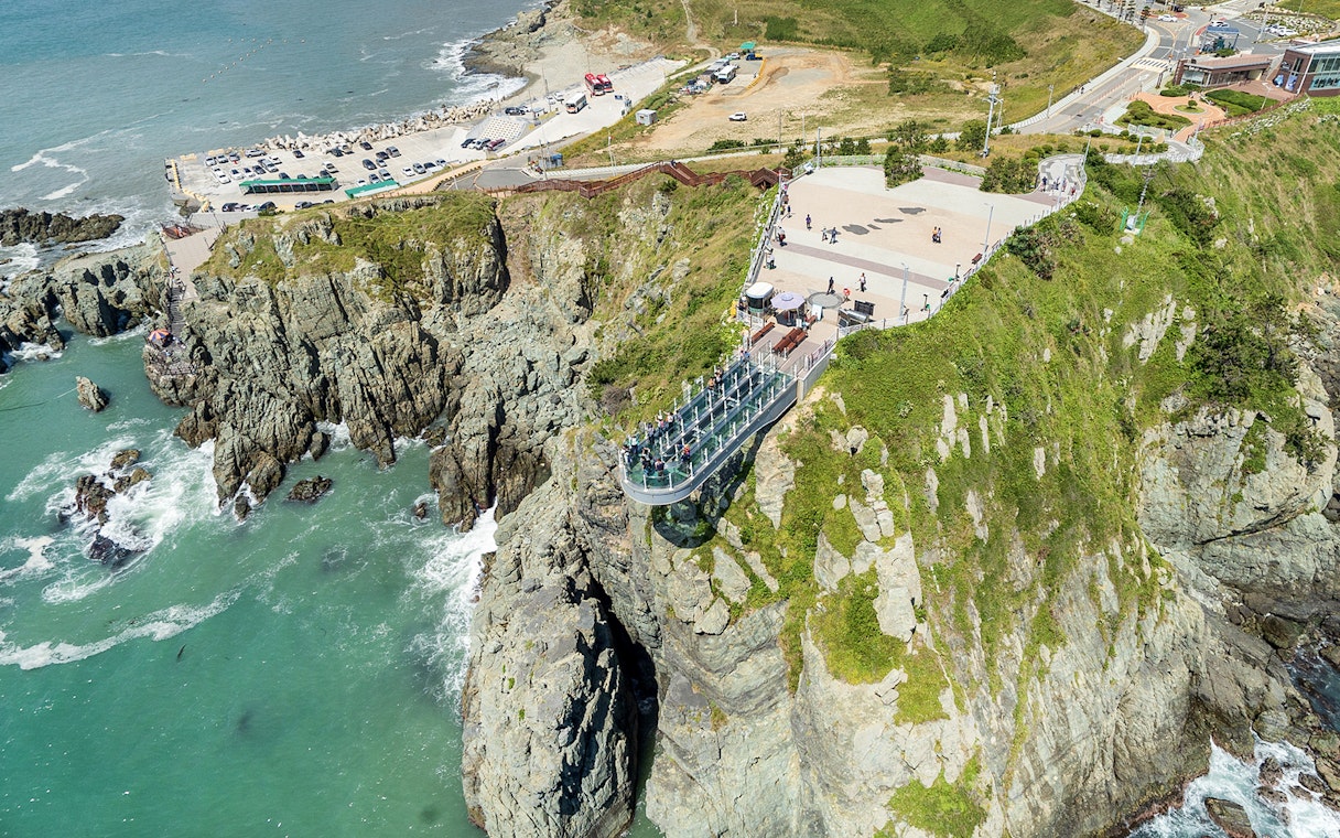 Cliffside view of Blueline Park Sky Capsule in Busan with ocean backdrop.