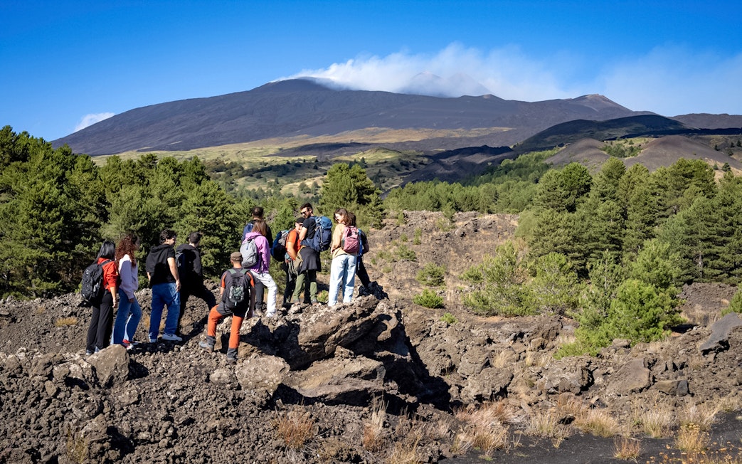 Group of hikers exploring volcanic landscape on Mount Etna during Catania morning tour.