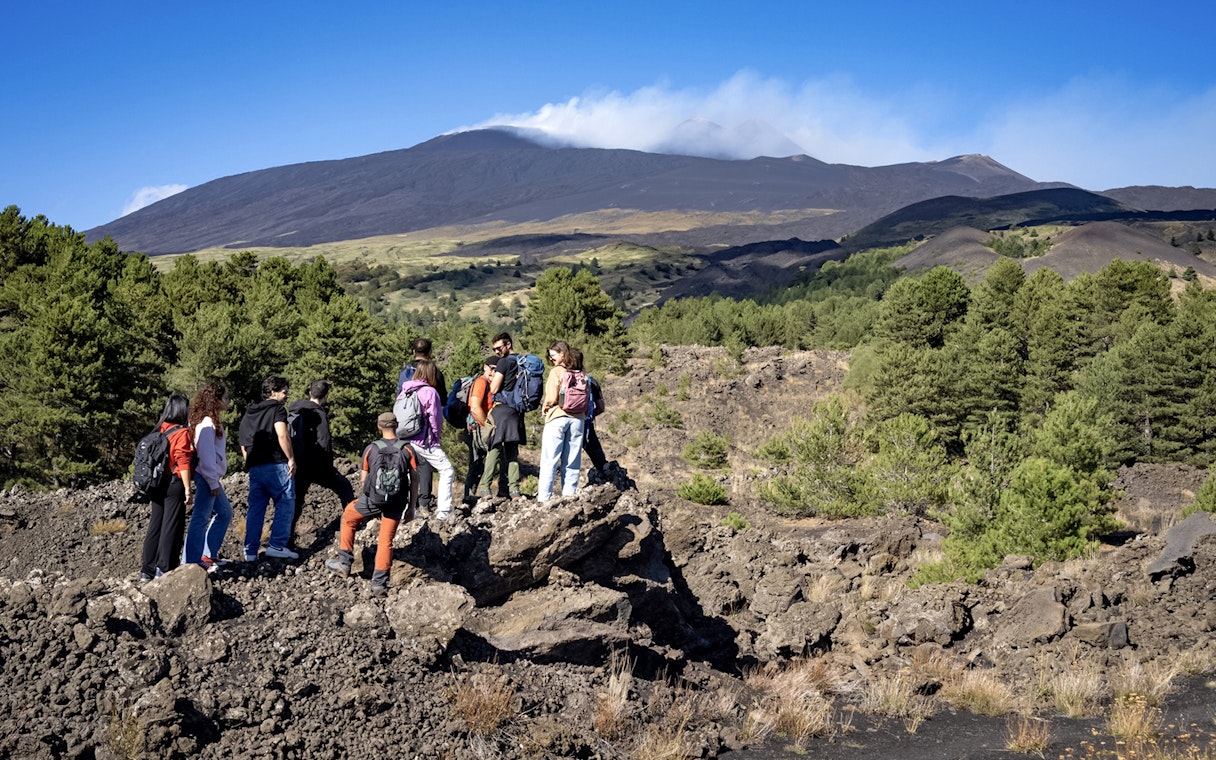 Group of hikers exploring volcanic landscape on Mount Etna during Catania morning tour.