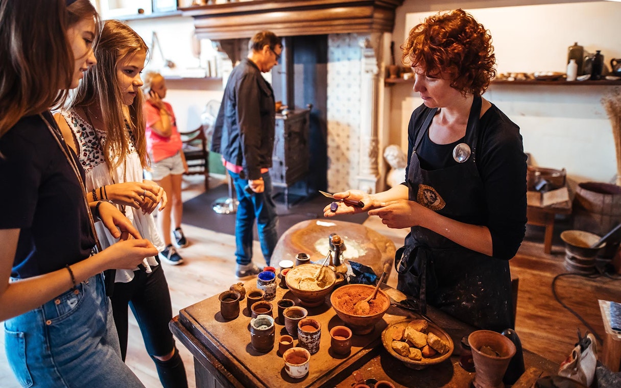 Guide demonstrating paint-making to visitors at Rembrandt House Museum.