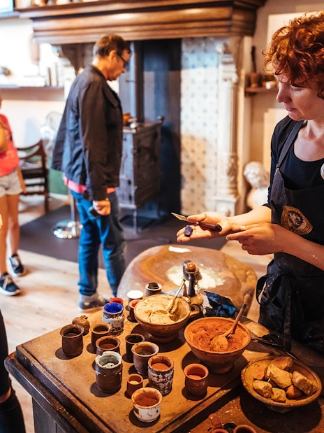 Guide demonstrating paint-making to visitors at Rembrandt House Museum.