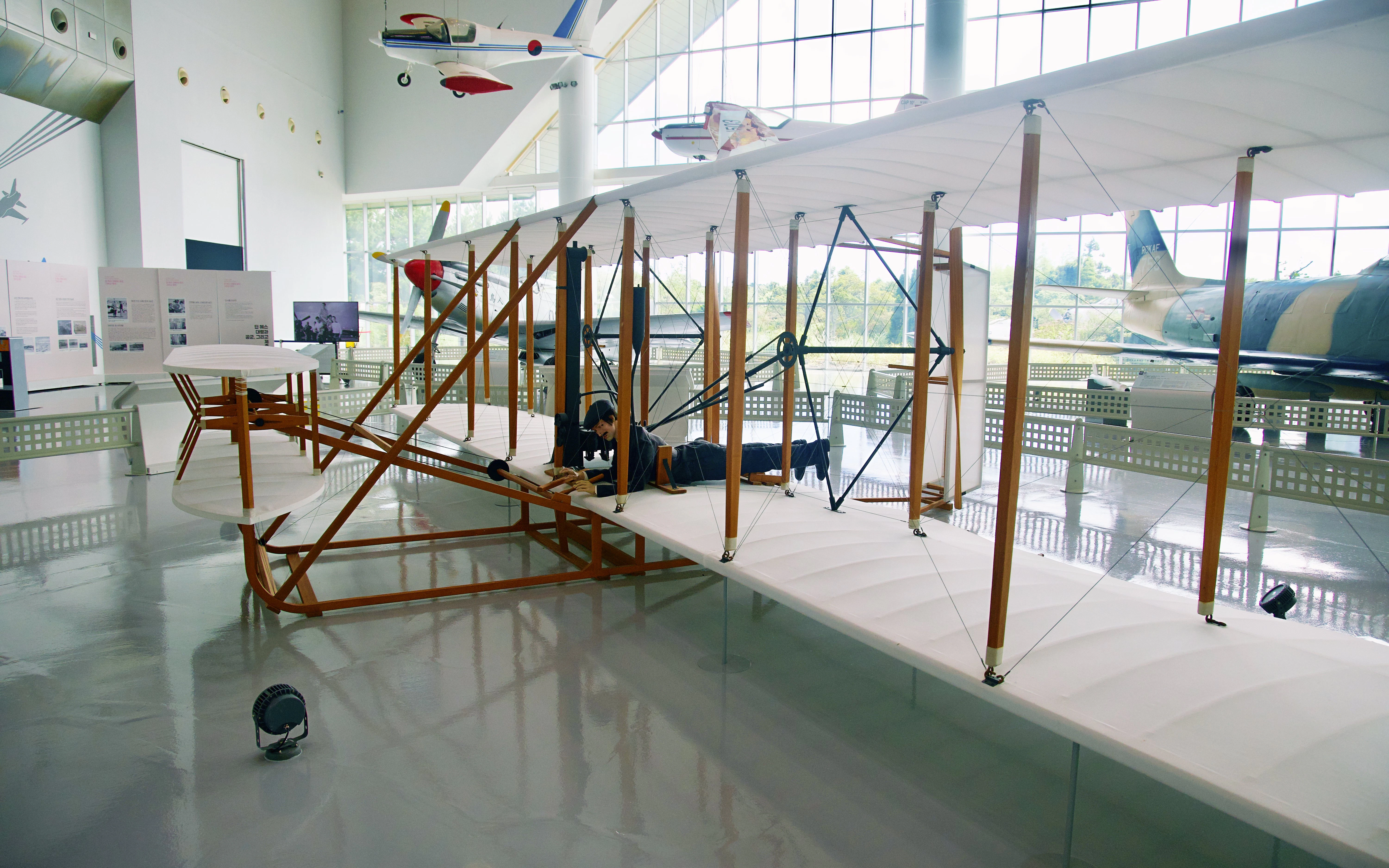 Wright Flyer replica on display in a museum setting with informational panels.