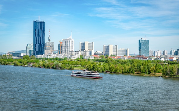 Cruise ship on the Danube River with Vienna skyline in the background.