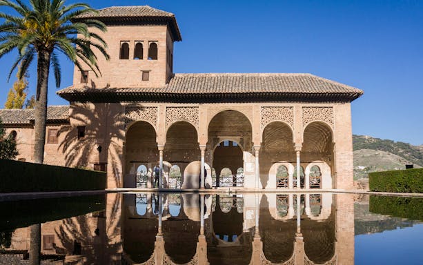 Alhambra's Nasrid Palaces with reflection in water, Granada, Spain.