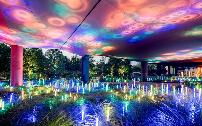 Colorful light installation at Musee du Quai Branly, Paris, illuminating garden area.