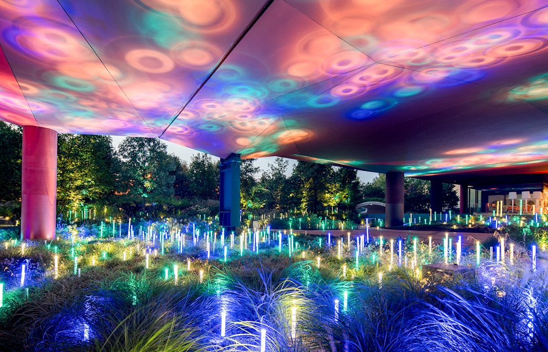 Colorful light installation at Musee du Quai Branly, Paris, illuminating garden area.