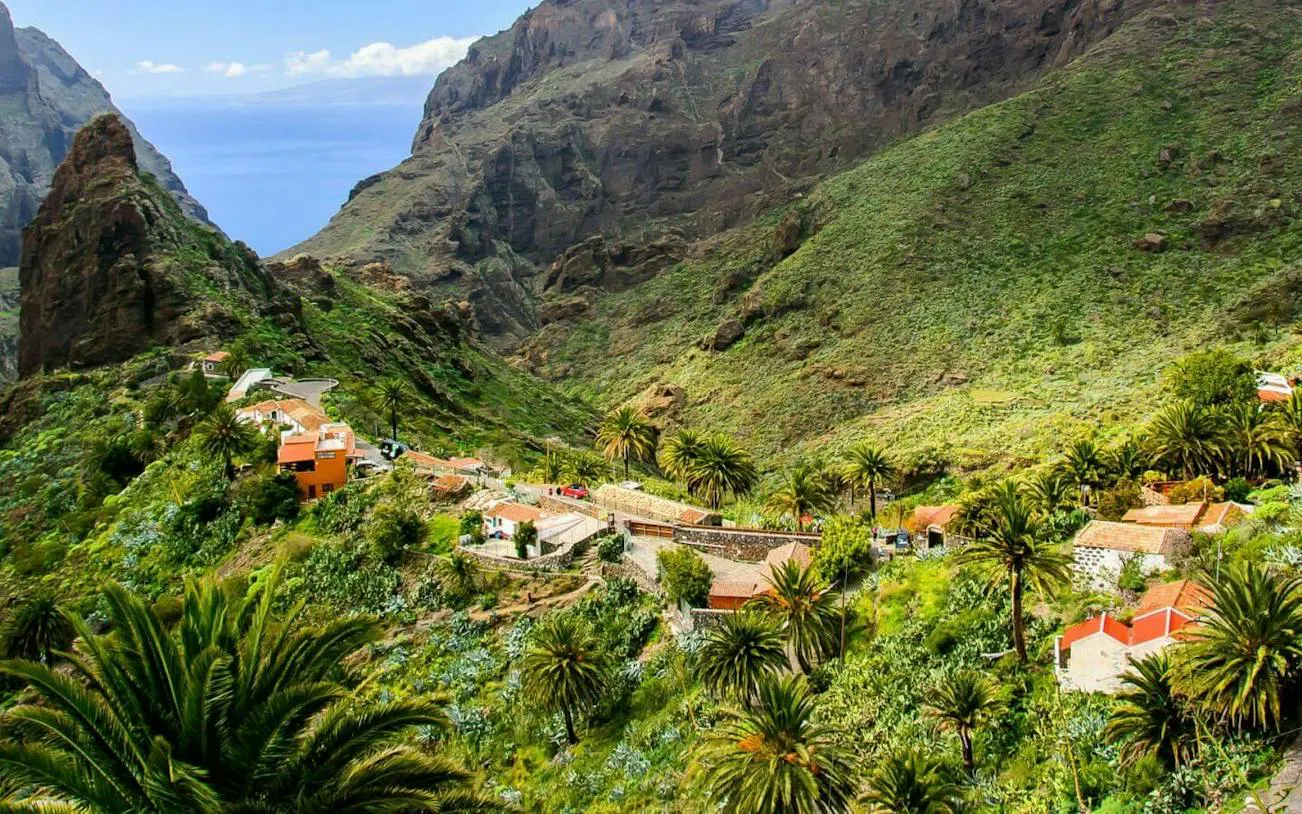 Masca Village nestled in lush green mountains, Tenerife, with palm trees and scenic views.